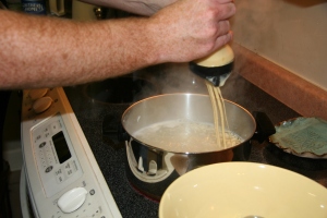 Spätzle batter squeezed out over a pot of boiling water